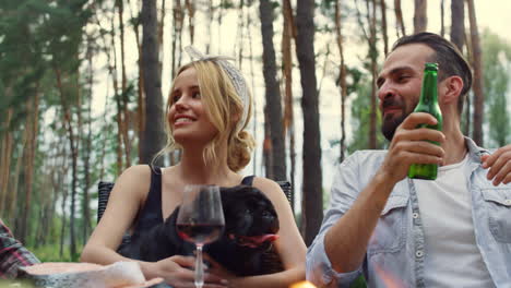 relaxed woman sitting with dog on hands outside. couple resting on summer party