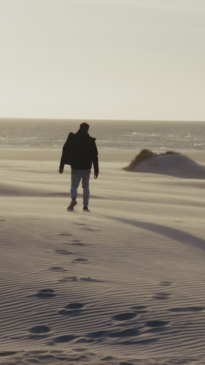 Man Walking on a Sandy Beach at Sunset