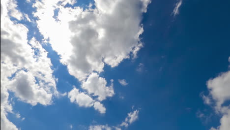 bright sun shining in blue sky. quickly flying white clouds against the sun. view from below. timelapse.