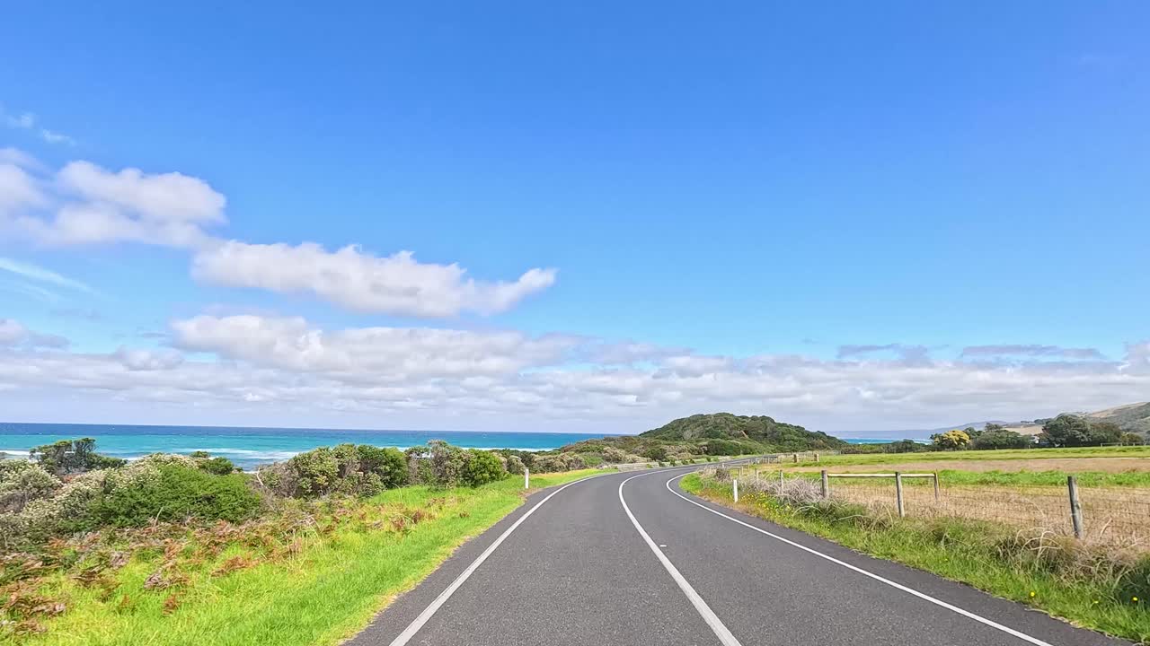 A serene drive on Great Ocean Road with lush greenery, clear skies, and winding paths, captured in bright daylight