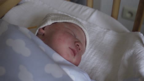 Cute-newborn-baby-sleeping-in-his-hospital-bed,-deep-sleep-while-wearing-his-winter-hat