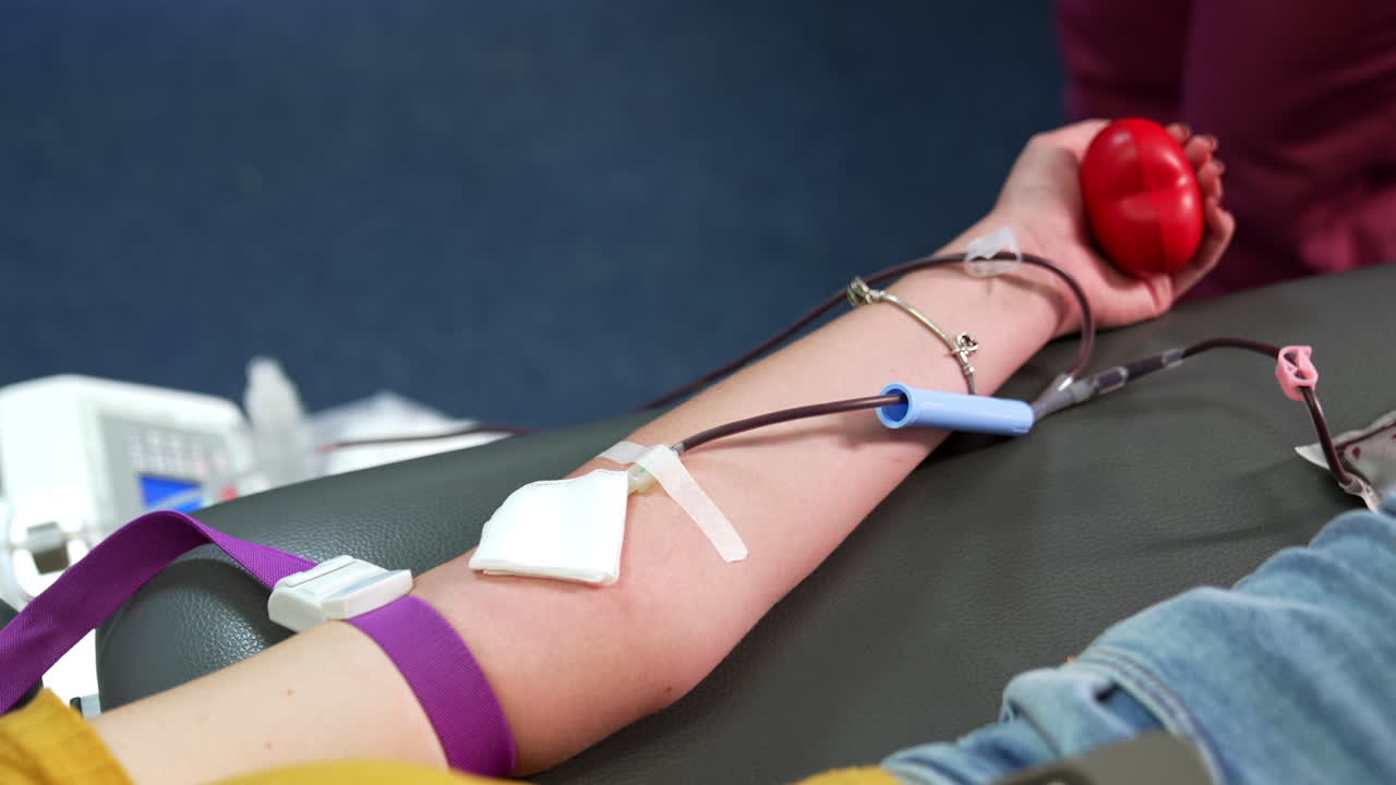 Blood runs by the tube of a catheter attached to the arm of a woman. Transfusion and donation of blood. Close up.