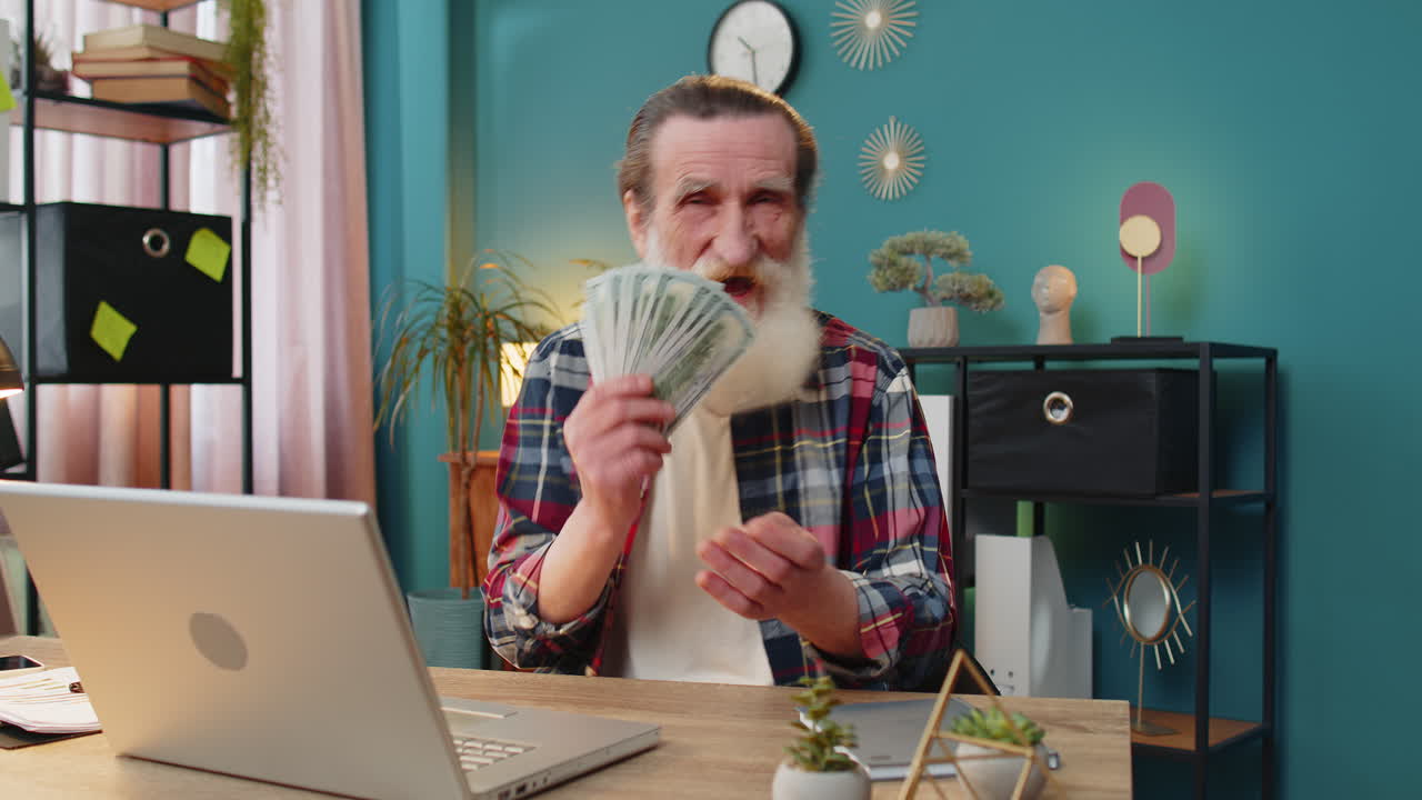 행복한 노인이 현금, 돈, 달러 지폐의 팬을 들고 엄지손가락을 올려 부를 축하합니다.