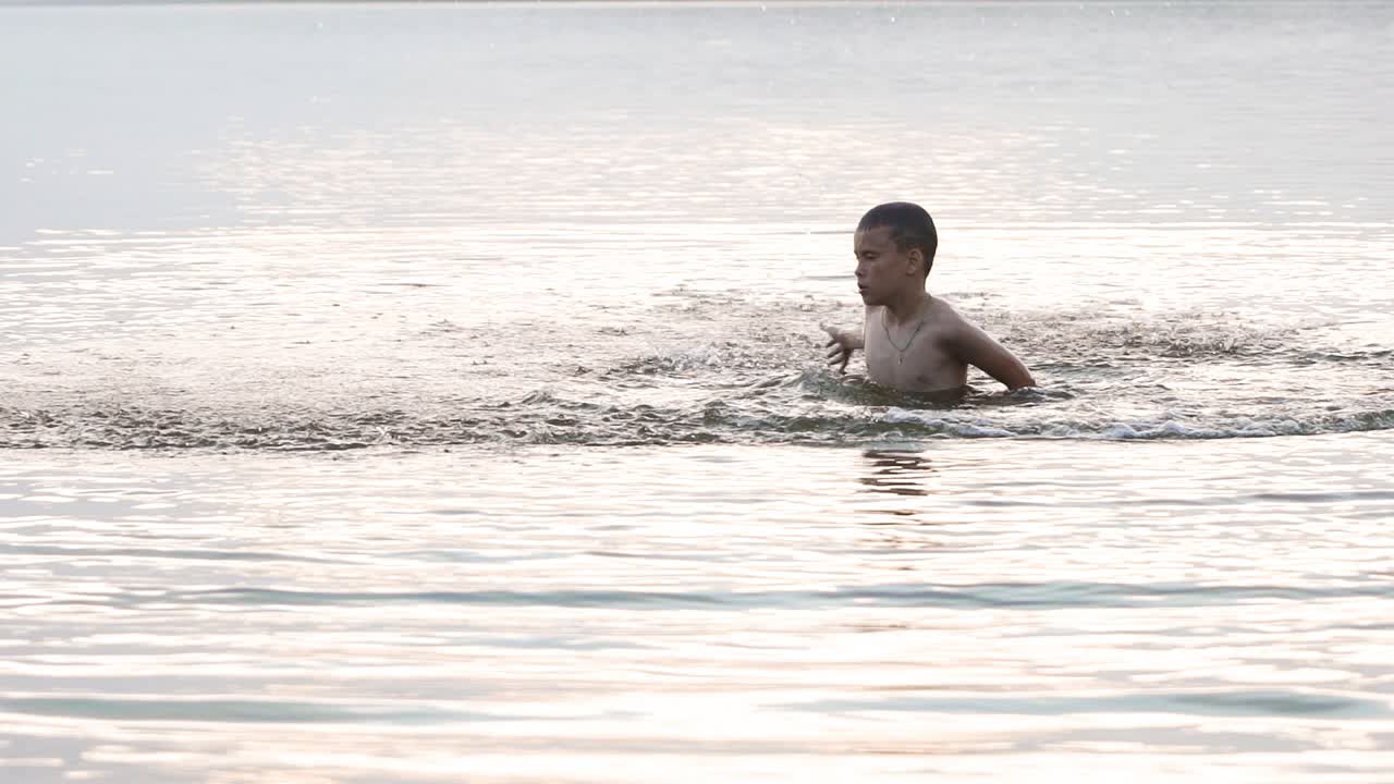 Slow motion of a child playing in the river. Happy boy having fun on vacation. Close-up shot of water splashes