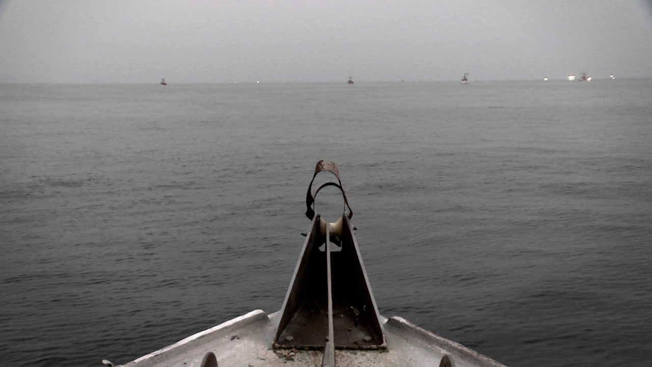 un barco pasa por el agua con un nadador y otros barcos en la distancia