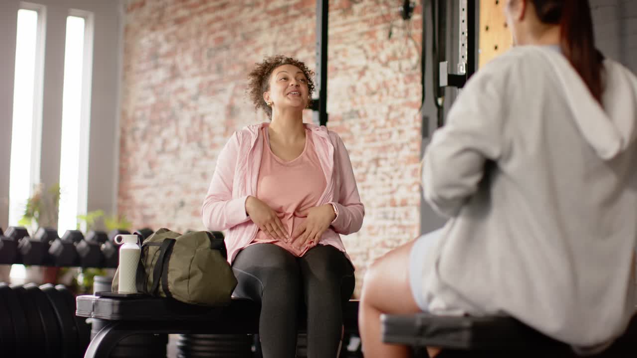 Kvindelig fitnessinstruktør guider klient i dyb vejrtrækning og placerer hænder på skuldrene ved træningsbænken