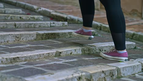 Close-up-of-the-feet-of-a-lone-female-tourist-walking-the-stairs-of-the-old-city-of-Perugia,-Province-of-Perugia,-Italy