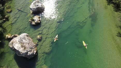 aerial view of a person in kayak on a green river. drone flying away from person in kayak and revealing a group of friends kayaking, swimming and having fun at a tarn river valley in millau, france
