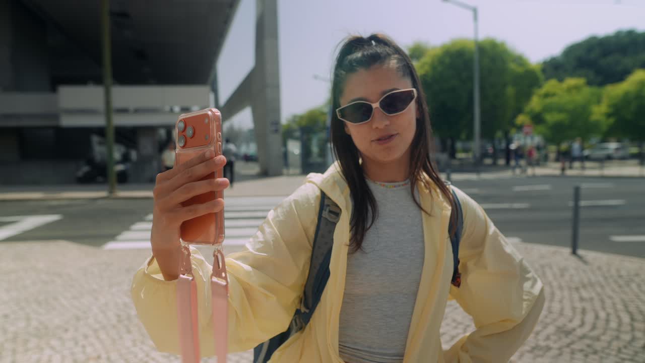 Ung kvinne vlogger med smarttelefon i en solrik by