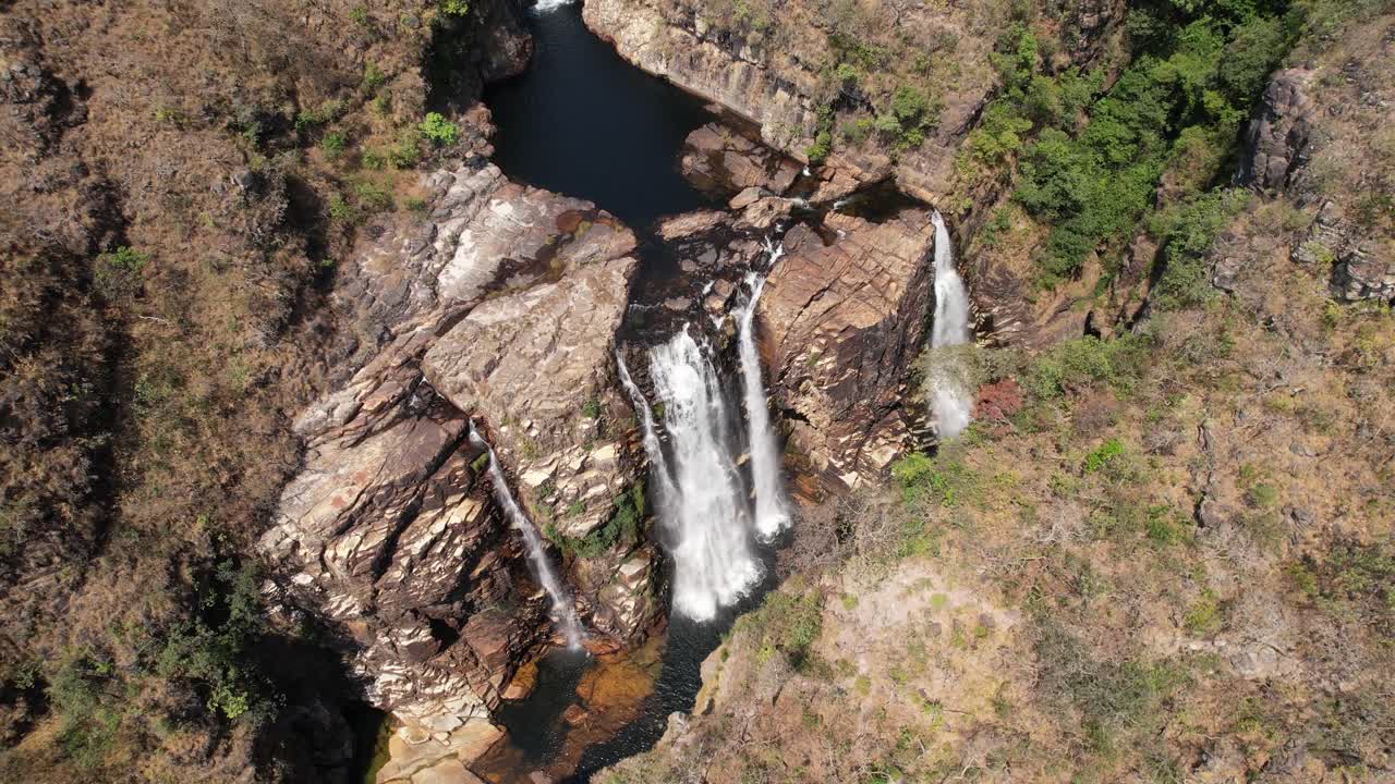 drone top view video of Cataratas dos Couros, Almecegas 1000 waterfall, beautiful waterfall with large rocks and trees, Chapada dos Veadeiros, Goiás, Brazil