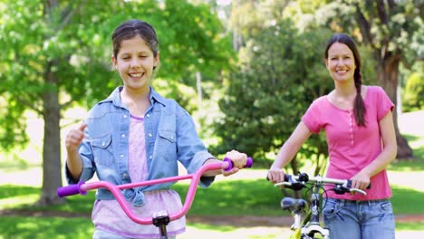 Linda-Madre-E-Hija-En-Un-Paseo-En-Bicicleta-Por-El-Parque-Juntas