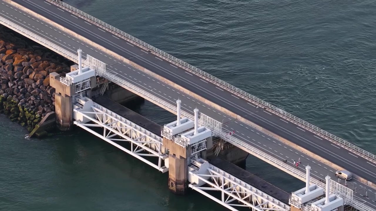 Luftfoto af Oosterschelde stormflodsbarriere og vej i Zeeland, Holland, der viser kystbeskyttelse mod oversvømmelser og Delta Works infrastruktur.
