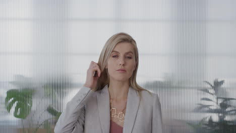 portrait attractive young blonde business woman preparing for meeting fixing hair looking confident in stylish corporate fashion slow motion office background