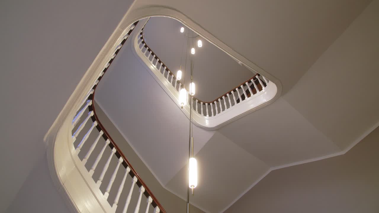 A staircase in a historic minimalistic scandinavian building in Copenhagen with designer lamps from the celling