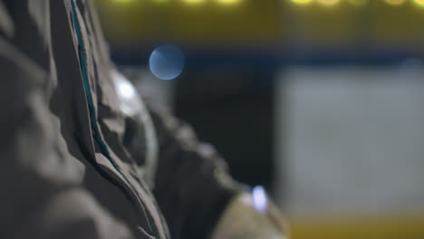 close-up of gloved hand clenched into a fist, capturing intricate glove details with a soft focus background of blurred lights and muted tones