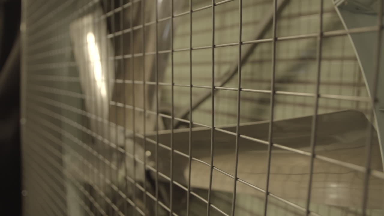 de un ventilador de club nocturno gigante en una jaula en la oscuridad detrás de una parrilla o valla de pie todavía tiro de tronco