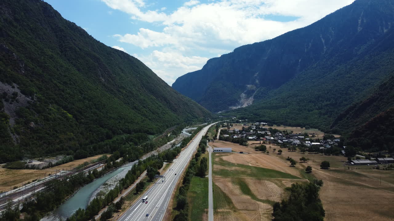 Aerial view of a valley with highway, river, and village