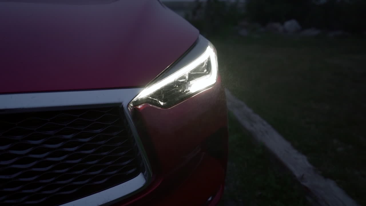 춥고 약간 안개가 자욱한 밤 동안 크롬 디테일과 검은색 그릴이 있는 빨간 자동차의 장대한 근접 촬영 사진