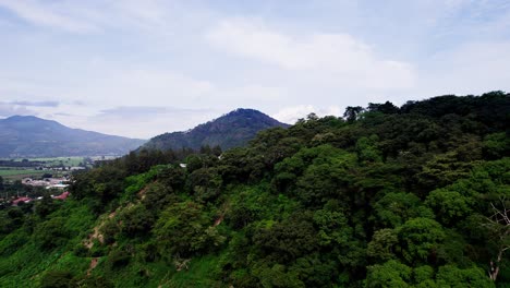 Aerial-dolly-above-mountain-ridgelines-outside-of-farming-village,-blue-sky-day