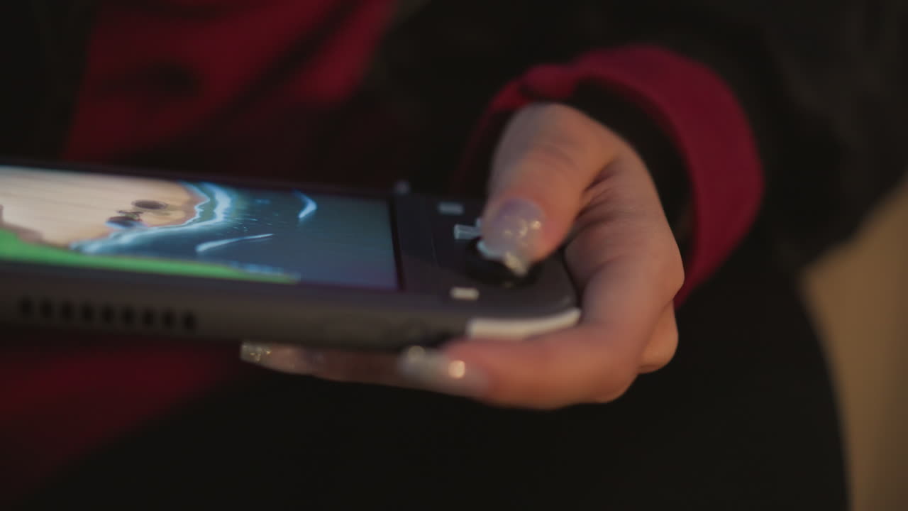 Joystick Guides Portable Game System, Display Shows Hand Using Joystick In Evening Light, Individual Uses Joystick To Browse Menu On Handheld Device Illuminated By Soft Evening Lighting