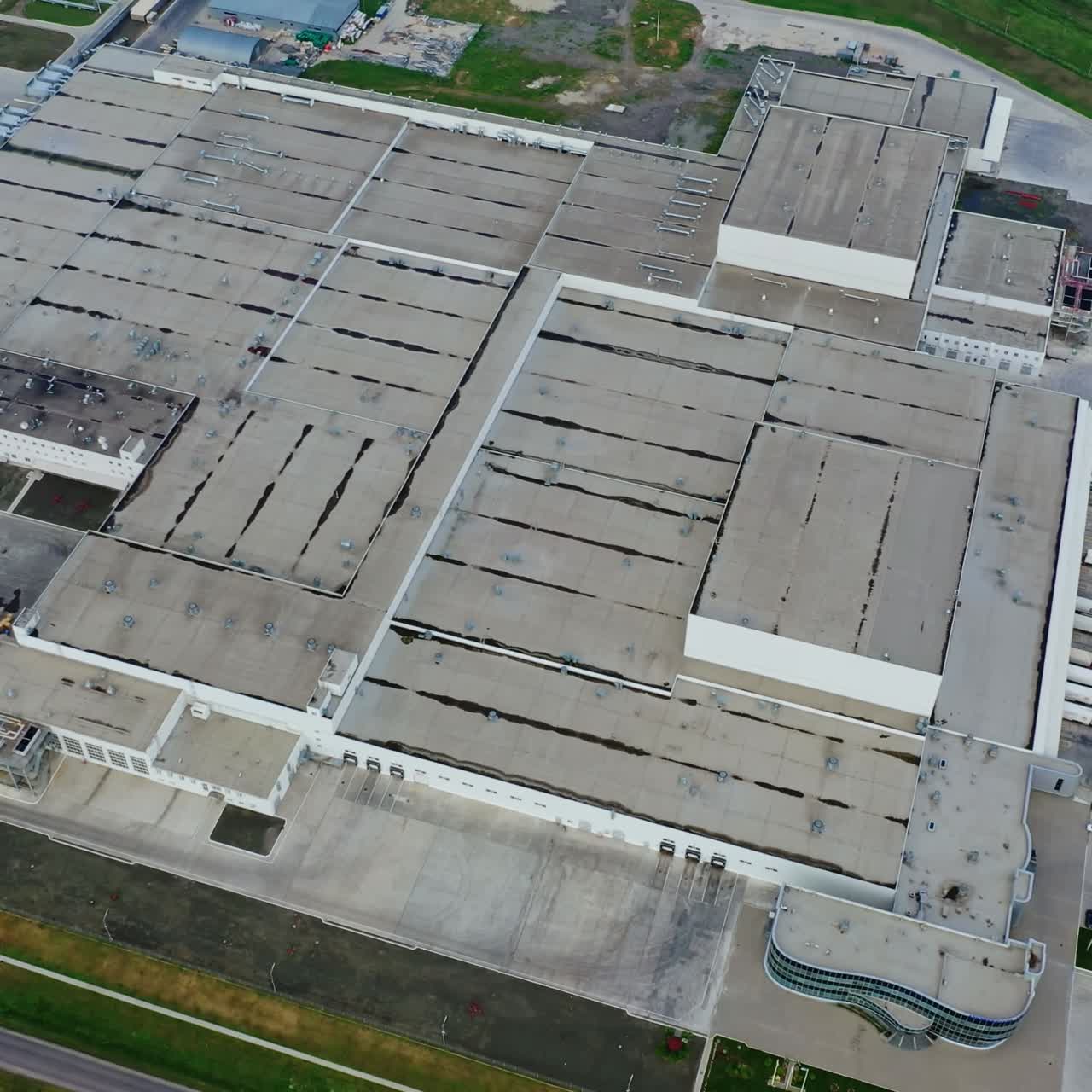 Industrial complex. View from above on roofs of buildings of manufacture. Large factory on green field. Drone descending down.