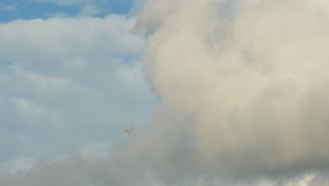a hot air balloon flying high and dives into a cloud