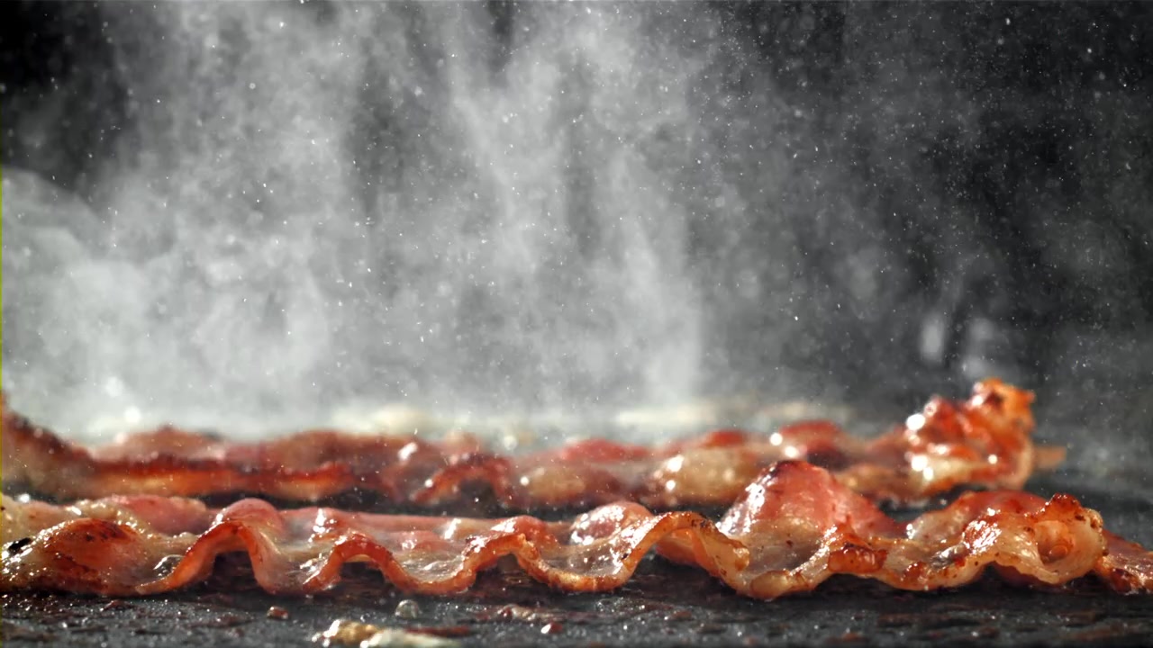 Pancetta a striscioline che sfrigola su una piastra calda