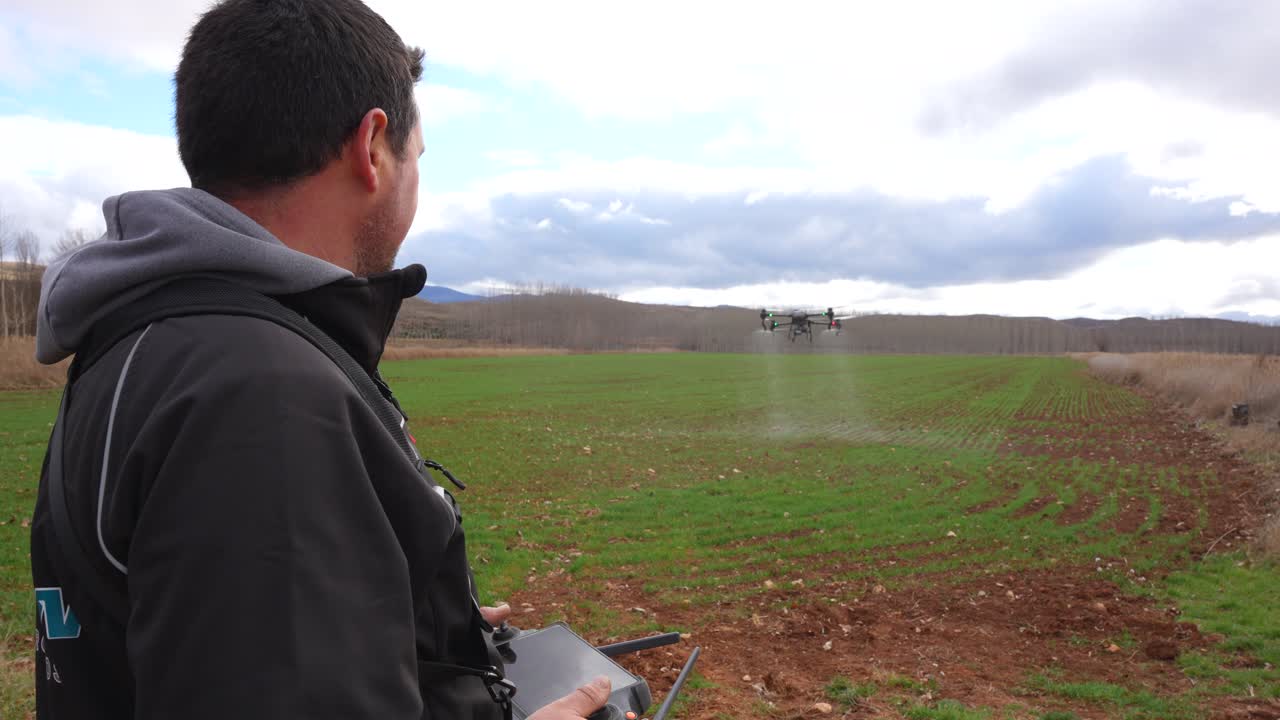 Fazendeiro pilota um grande drone agrícola irrigando um campo de trigo sob condições ensolaradas