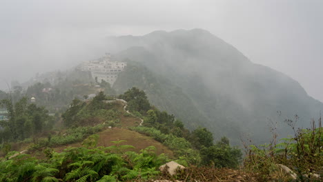 un video de lapso de tiempo de nubes moviéndose sobre las escarpadas montañas del himalaya en nepal con algunos edificios cubiertos por las nubes