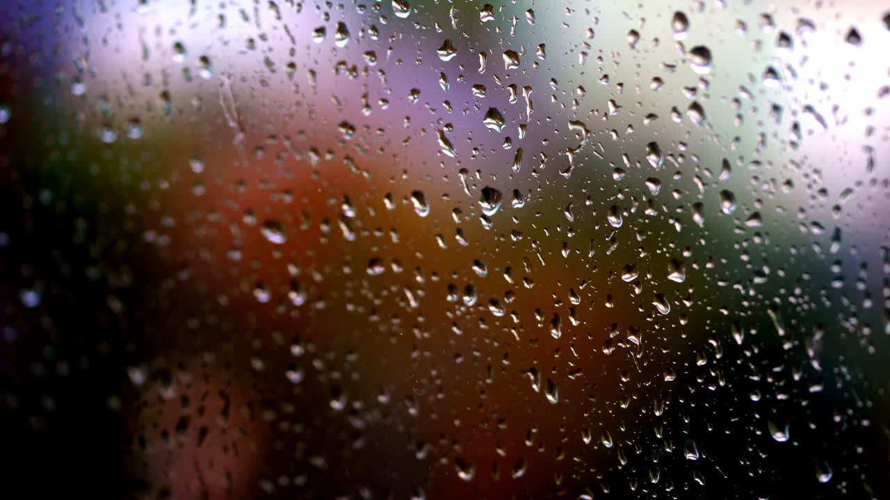 Water drops background. Rain drops on glass window in rainy season. Large raindrops strike on a window frame. Close-up.