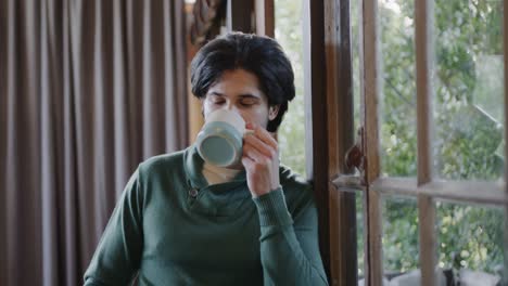 Caucasian-man-drinking-coffee-and-looking-out-window-at-home,-slow-motion