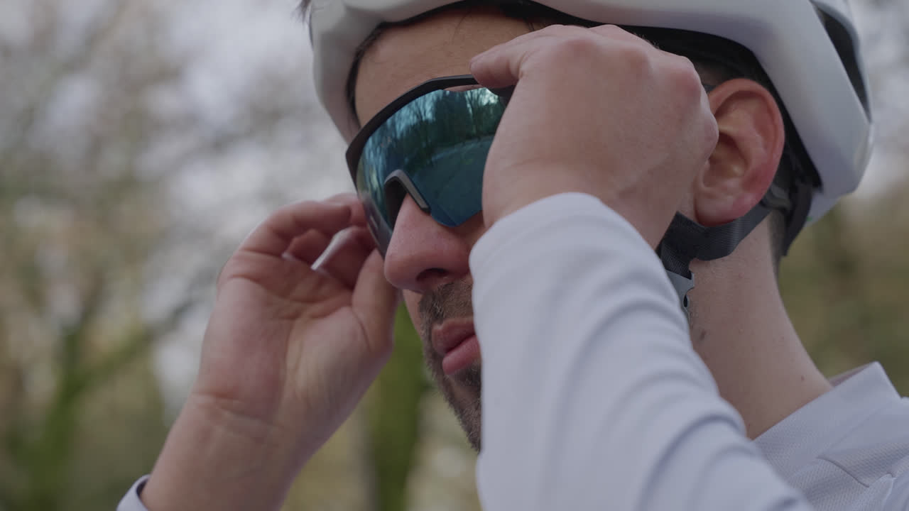 Primer plano de ciclista poniéndose gafas de sol deportivas al aire libre.