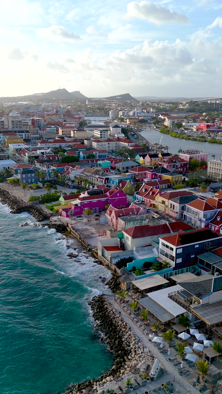 Vertical HD drone shot of Pietermaai coast during sunset with colorful seafront architecture and scenic shoreline.