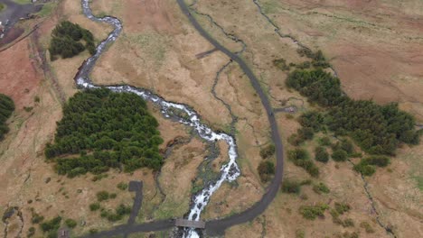 flying over the river flowing from the waterfall bjarnarfoss with a little bridge over the river and a path leading to the waterfall