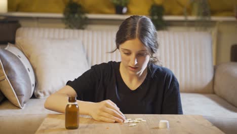 the young woman who takes the pills on the table with trembling hands. suicide.