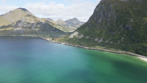 Bewegliche-Kamera-über-Dem-Meer-In-Richtung-Berge-Und-über-Dem-Weißen-Sandstrand-über-Dem-Türkisfarbenen-Wasser,-Das-Die-Sonne-Reflektiert