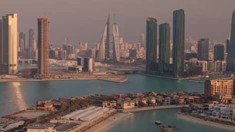 bahrain, aerial view over luxury waterside condos towards skyscrapers and downtown manama, warm late afternoon light