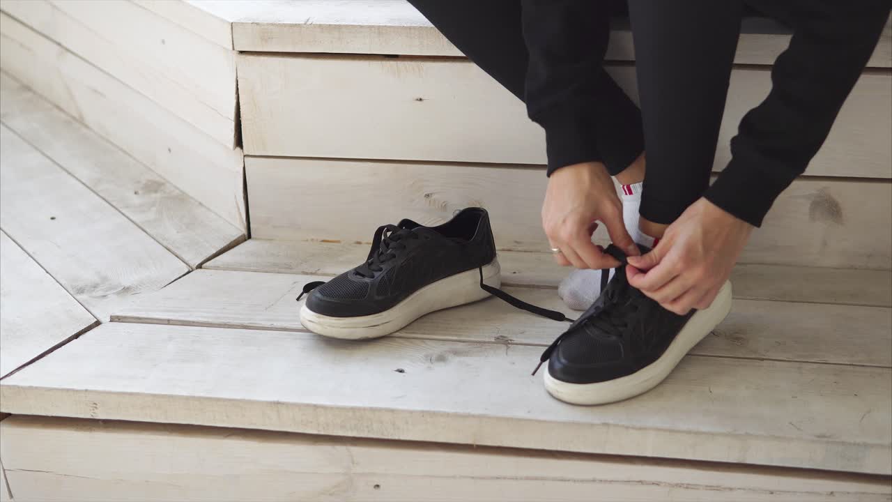Person Tying Shoes on a Wooden Platform