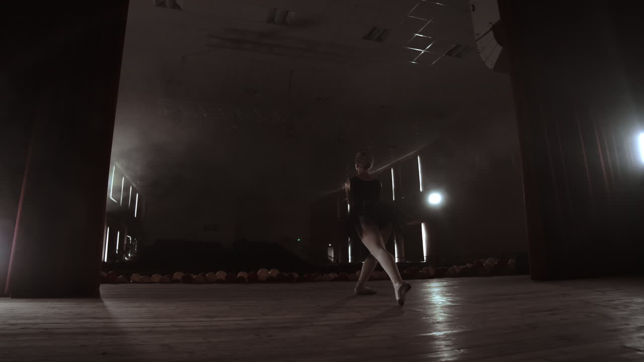 movimiento lento: prima ballet en un vestido negro realiza rotaciones y baila movimientos graciosos ensayando un programa en solitario. la cámara se mueve en gimbal.