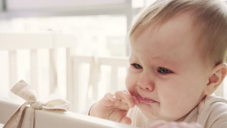 sad baby girl gnawing baby cot