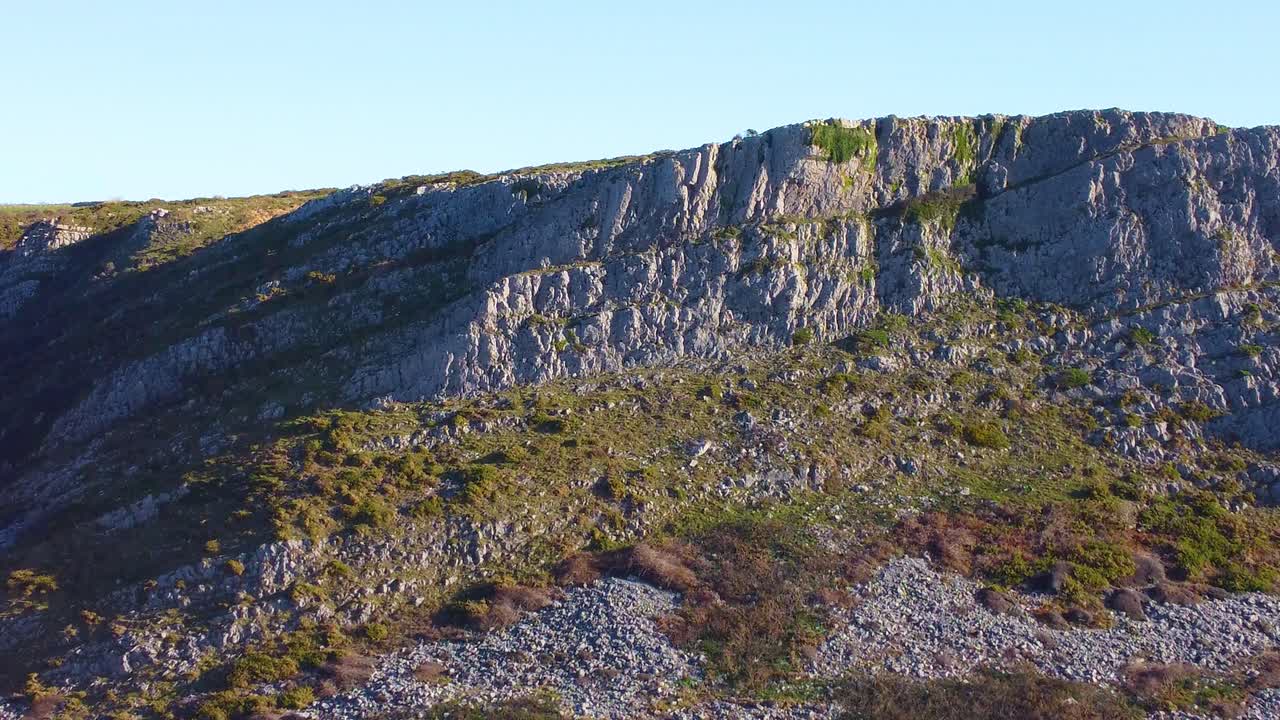 Pushing Aerial with Deep Shadows in Valley with Steep Terrain with Clear Blue Sky. Travel Nature Drone Clip. Beautiful Welsh Gower Peninsula Coast