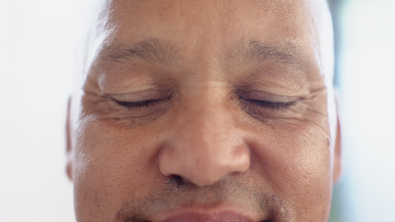 Smiling man with prosthetic eye looking directly at camera, close-up shot