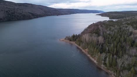 Drone-shot-of-the-Bra's-D'or-Lake-with-a-sandy-beach-and-view-of-trees