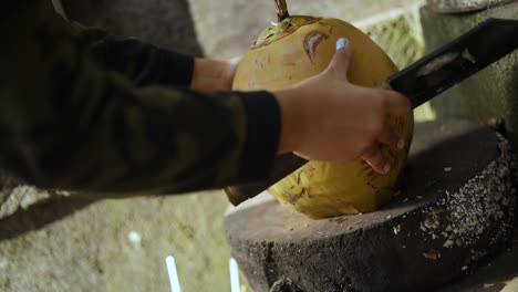 Close-Up-Shot-of-a-person-cutting-open-a-fresh-coconut-with-a-machete