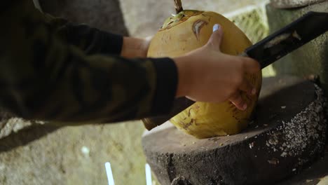 primer plano de una persona cortando un coco fresco con un machete