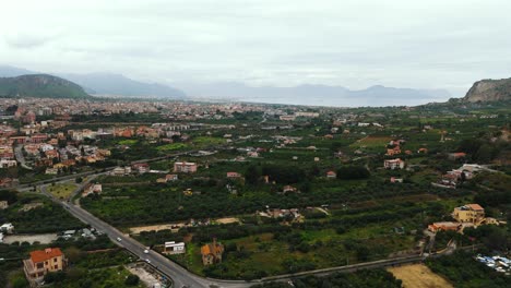 top-down aerial shot of intersecting streets in porticello near palermo, showing mediterranean-style homes, parked cars, and urban patterns in a quiet residential district