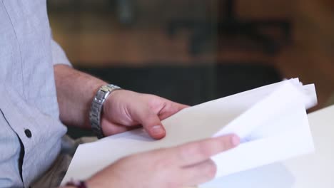 a man sitting in his room at his desk holding some papers, this man is in a meeting with another person and talking to him