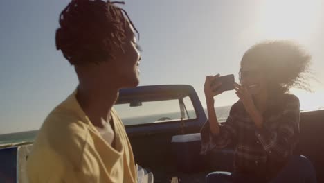 vista frontal de una mujer afroamericana tomando una foto de un hombre con un teléfono móvil