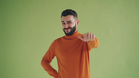 man in orange sweater giving a disapproving thumbs down