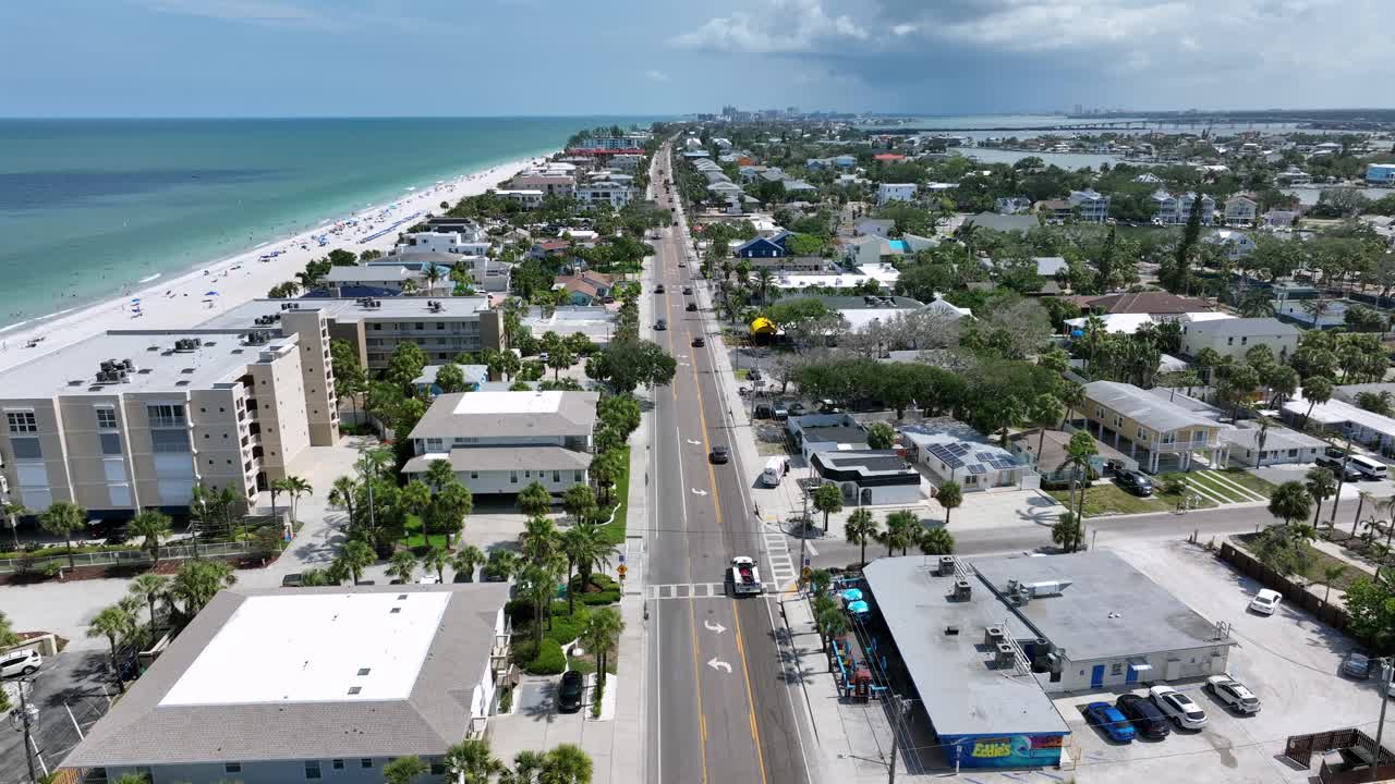 Straight street along sandy beach of Indian Rocks, Florida. Palm trees, apartment blocks in first row and clear water of Gulf Sea. Aerial wide shot.